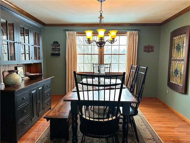 dining space with light wood-style floors, baseboards, a chandelier, and crown molding