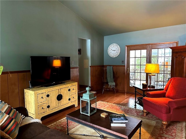 living area with lofted ceiling, wainscoting, wooden walls, and wood finished floors