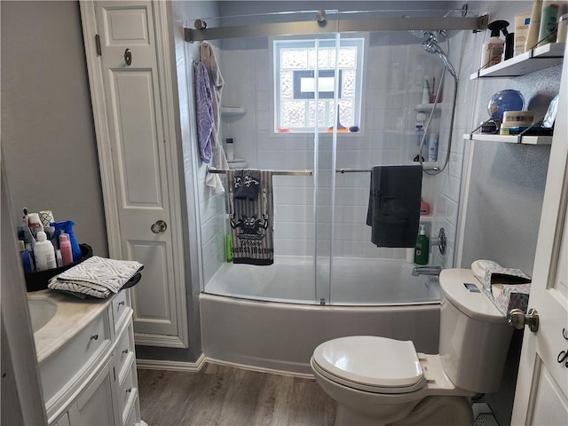 bathroom with shower / bath combination with glass door, a closet, toilet, vanity, and wood finished floors