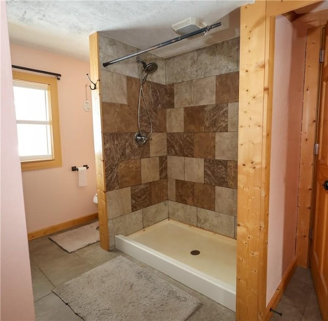 bathroom with a tile shower and baseboards