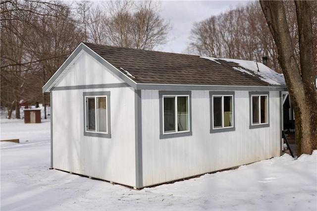 snow covered property with roof with shingles