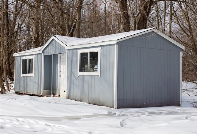 snow covered structure with an outbuilding