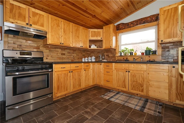 kitchen with under cabinet range hood, vaulted ceiling, stainless steel gas stove, open shelves, and dark countertops