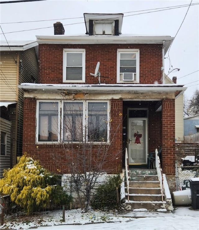 traditional style home featuring entry steps, brick siding, fence, and cooling unit