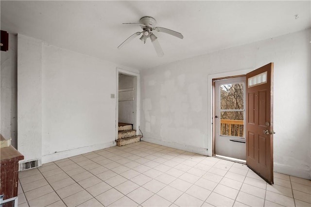 unfurnished room featuring a ceiling fan, visible vents, stairway, and baseboards