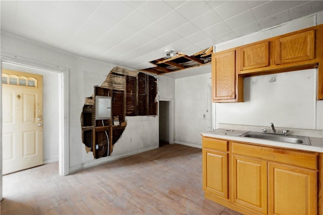 kitchen featuring brown cabinets, light wood-style flooring, light countertops, and a sink