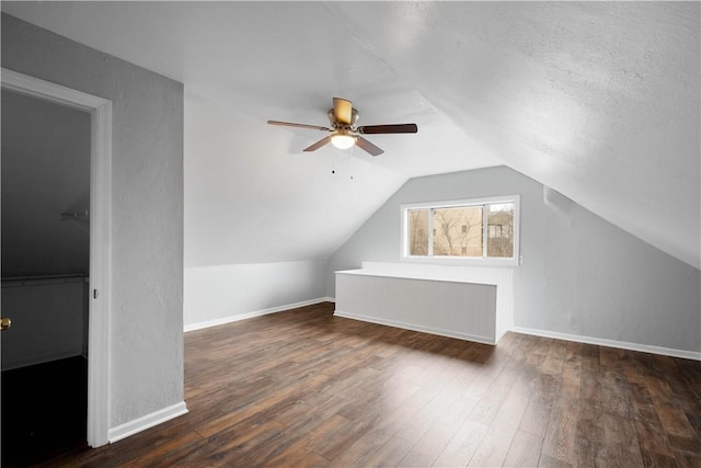 additional living space with vaulted ceiling, dark wood finished floors, and baseboards