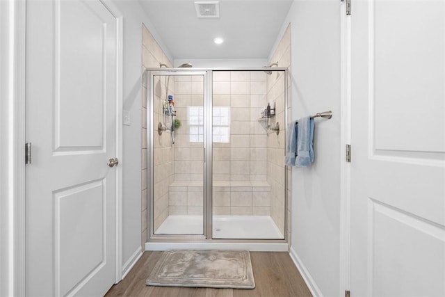 full bath with baseboards, a shower stall, visible vents, and wood finished floors