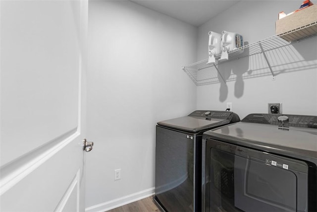 laundry room with laundry area, baseboards, separate washer and dryer, and wood finished floors