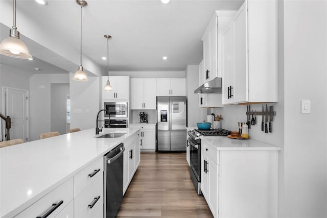 kitchen with pendant lighting, stainless steel appliances, light countertops, and under cabinet range hood