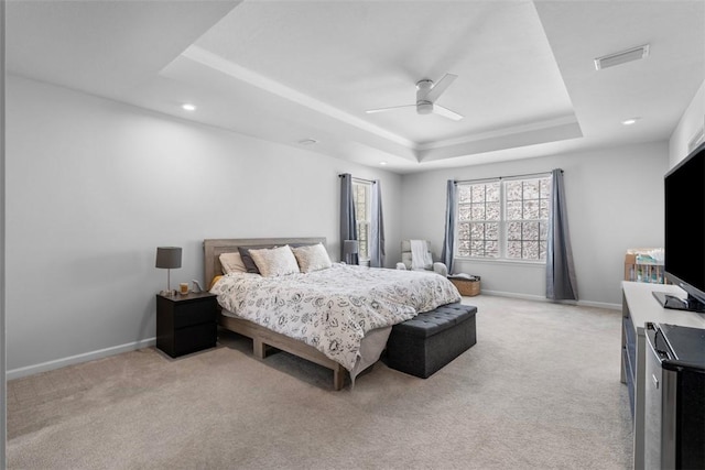 bedroom featuring light carpet, a raised ceiling, visible vents, and baseboards