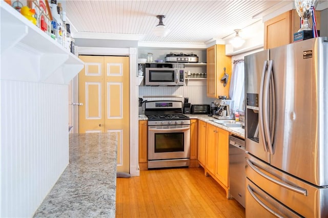 kitchen with open shelves, appliances with stainless steel finishes, a sink, light stone countertops, and light wood-type flooring