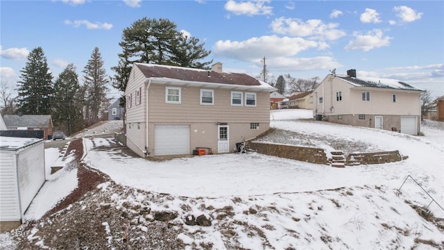 snow covered property featuring an attached garage and a chimney