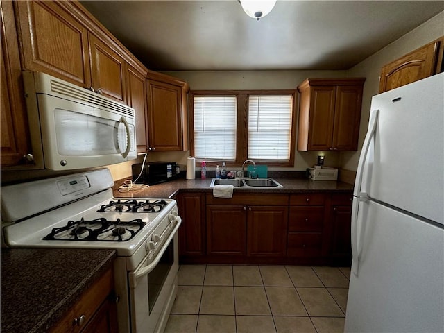 kitchen featuring light tile patterned floors, white appliances, brown cabinetry, and a sink