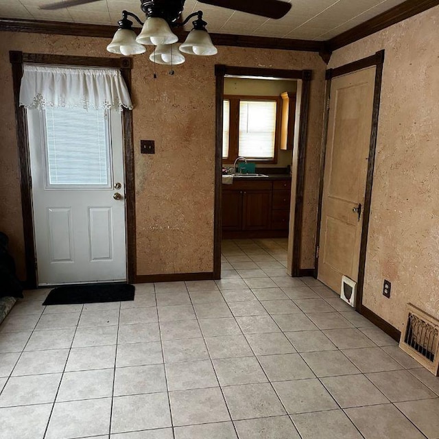 interior space with light tile patterned floors, visible vents, baseboards, crown molding, and a sink