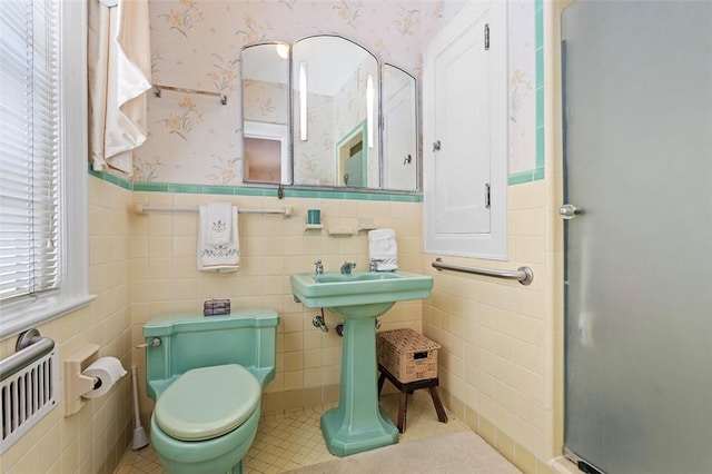 bathroom featuring wallpapered walls, wainscoting, toilet, tile patterned floors, and tile walls