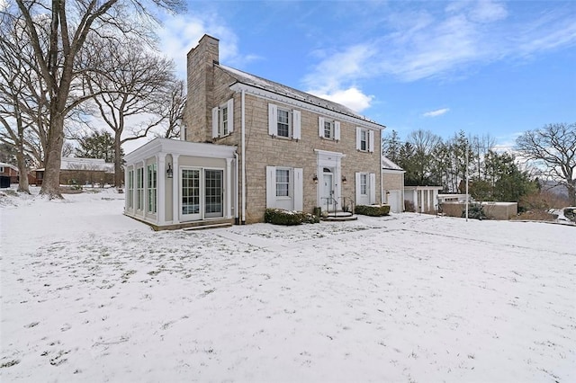 snow covered rear of property featuring a chimney