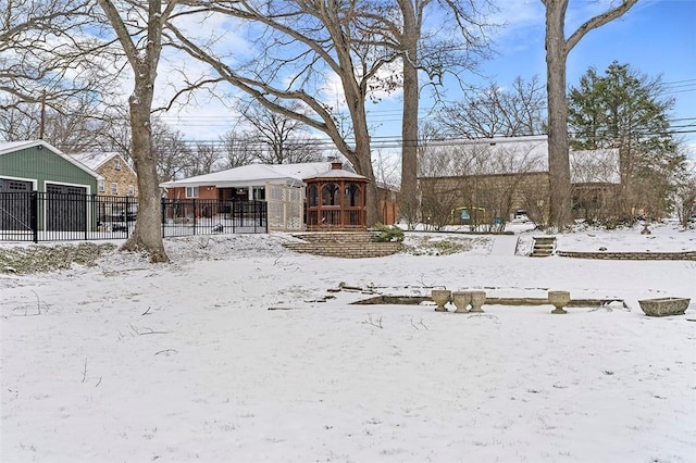 yard layered in snow featuring a garage and fence