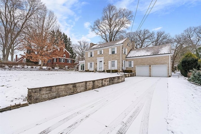 colonial home with a chimney and an attached garage