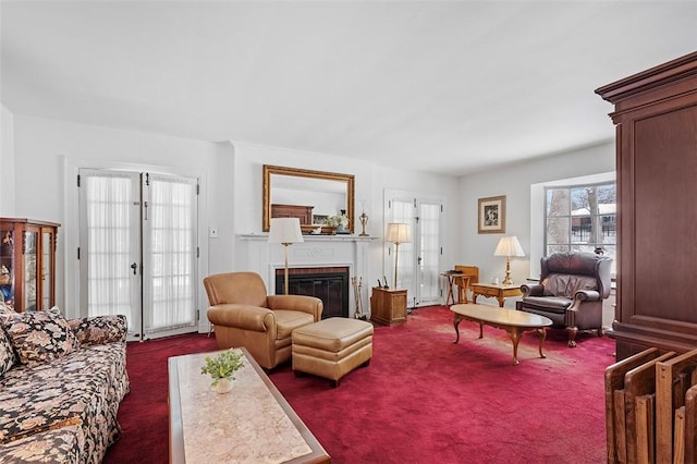 living area featuring dark colored carpet, french doors, and a glass covered fireplace