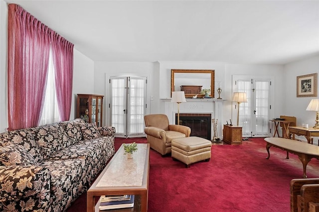 living area with a fireplace with flush hearth, a wealth of natural light, and dark colored carpet