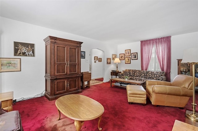 living area with carpet floors, arched walkways, and baseboards