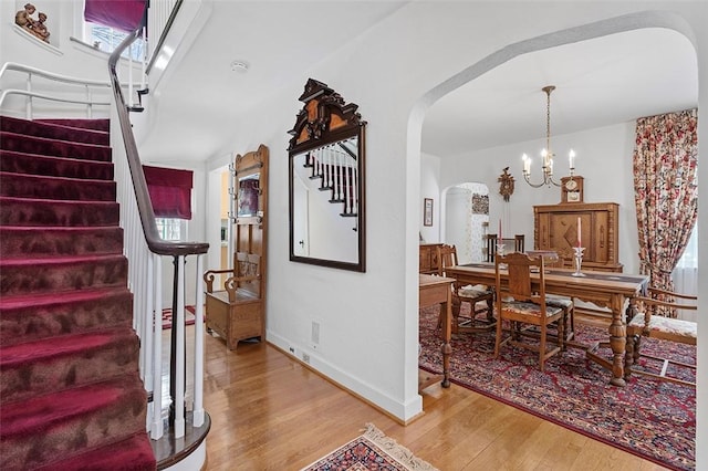 interior space with arched walkways, a chandelier, wood finished floors, and baseboards