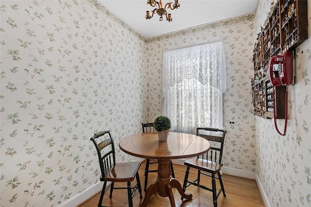 dining area with a chandelier, wood finished floors, baseboards, and wallpapered walls