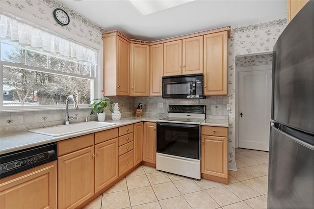 kitchen featuring range with electric stovetop, light countertops, freestanding refrigerator, a sink, and black microwave