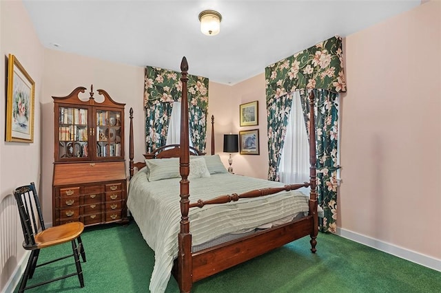 bedroom with dark colored carpet and baseboards