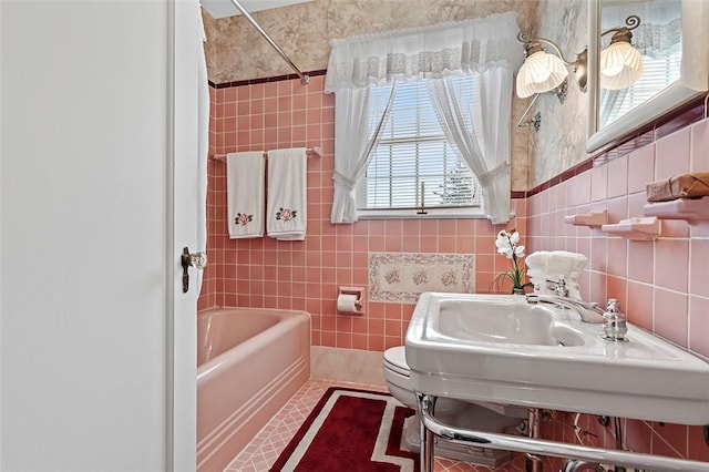 bathroom featuring bathtub / shower combination, a sink, tile walls, and toilet