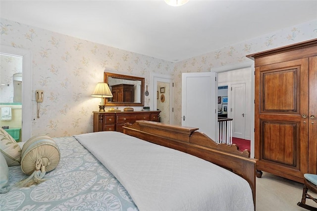 bedroom featuring light carpet, wallpapered walls, and connected bathroom