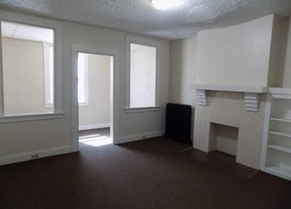 unfurnished living room featuring a fireplace, baseboards, and a textured ceiling