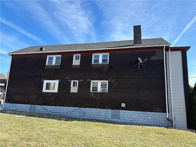 rear view of property featuring crawl space, brick siding, a lawn, and a chimney