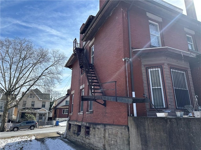 view of snowy exterior featuring brick siding and fence