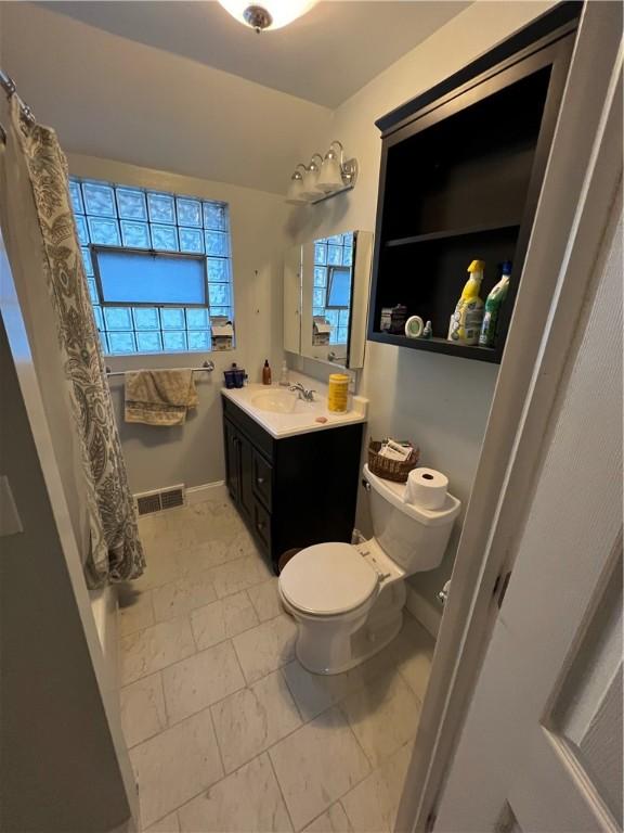 bathroom with toilet, vanity, visible vents, and baseboards