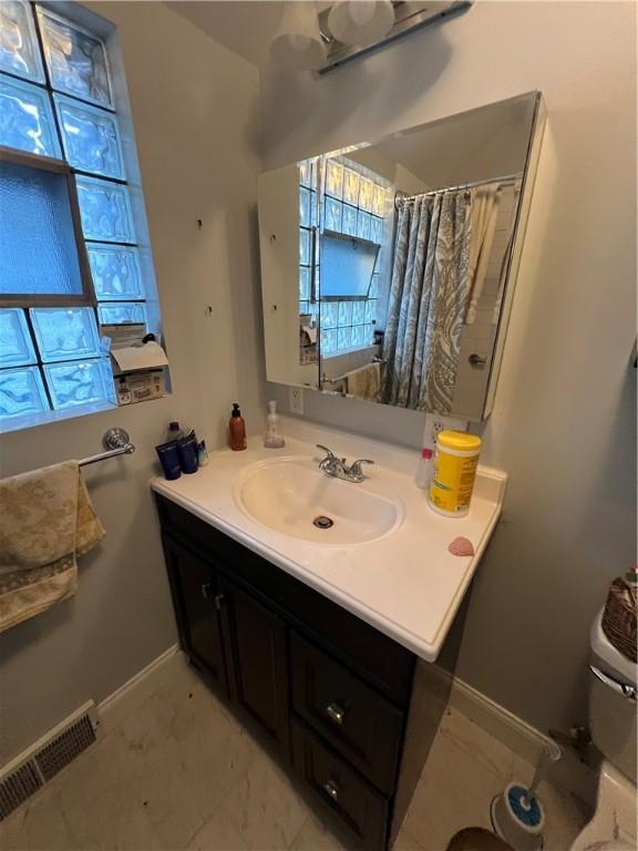 full bath featuring toilet, baseboards, visible vents, and vanity