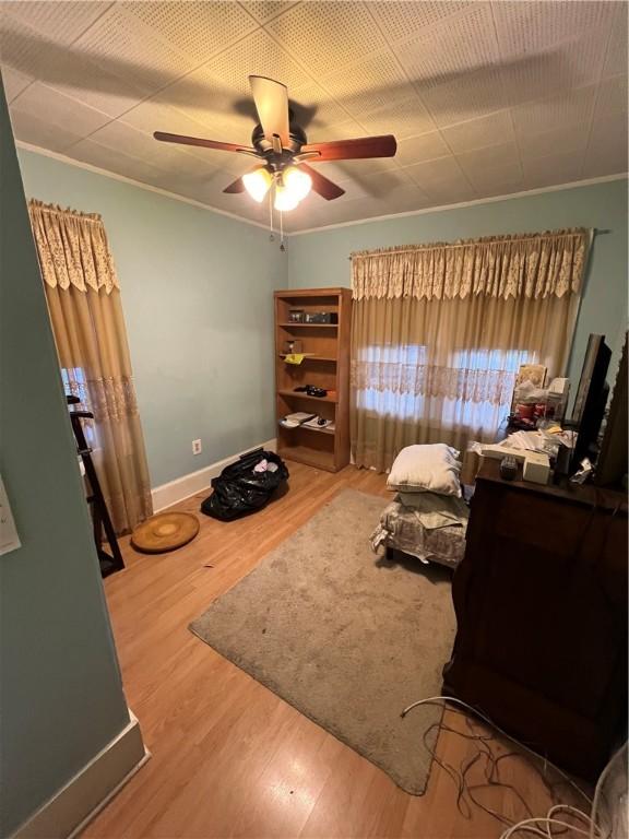 bedroom featuring ornamental molding, ceiling fan, baseboards, and wood finished floors