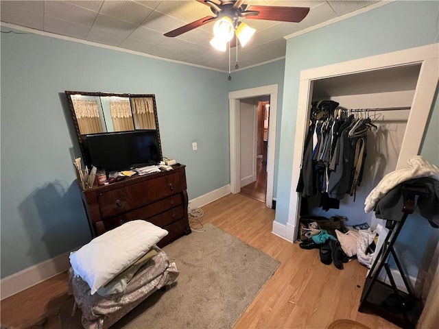 bedroom with a closet, crown molding, light wood-style flooring, and baseboards