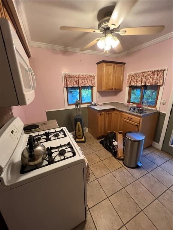 kitchen with ceiling fan, light tile patterned floors, white appliances, ornamental molding, and brown cabinetry