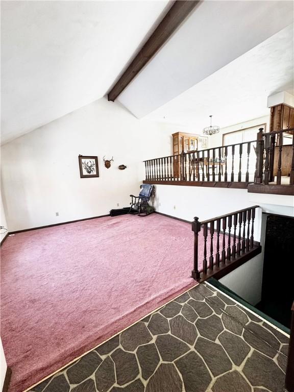 interior space featuring carpet flooring, lofted ceiling with beams, and an inviting chandelier