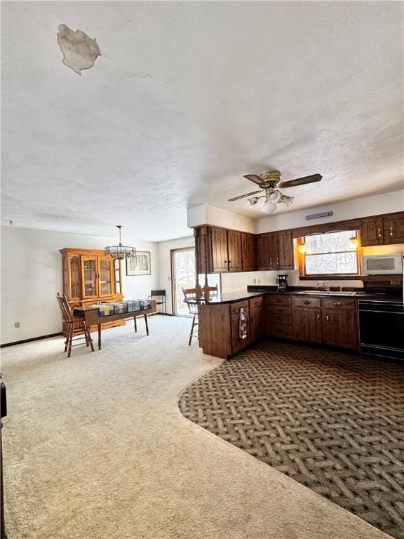 kitchen featuring dark brown cabinetry, range with electric cooktop, a ceiling fan, white microwave, and carpet flooring