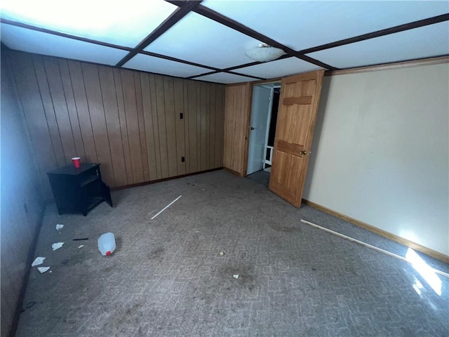 unfurnished bedroom with carpet flooring, wood walls, and baseboards