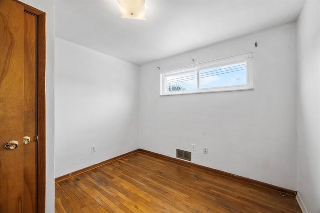 unfurnished room with wood finished floors, visible vents, and baseboards