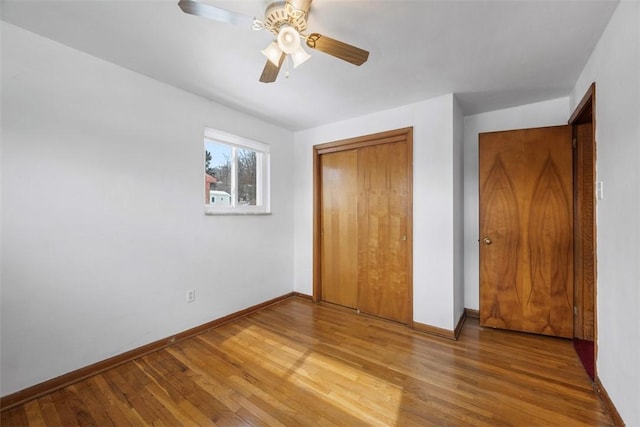 unfurnished bedroom featuring ceiling fan, a closet, wood finished floors, and baseboards