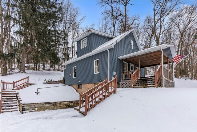 snow covered rear of property with stairway