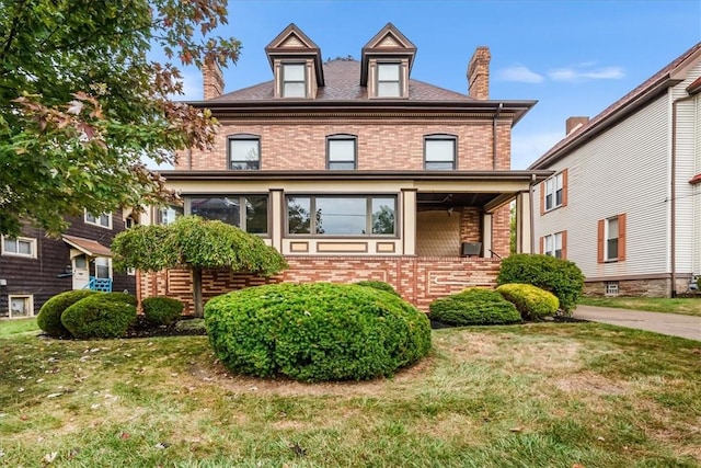 american foursquare style home with brick siding, a chimney, and a front yard