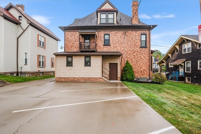 rear view of property featuring a yard, brick siding, and a chimney