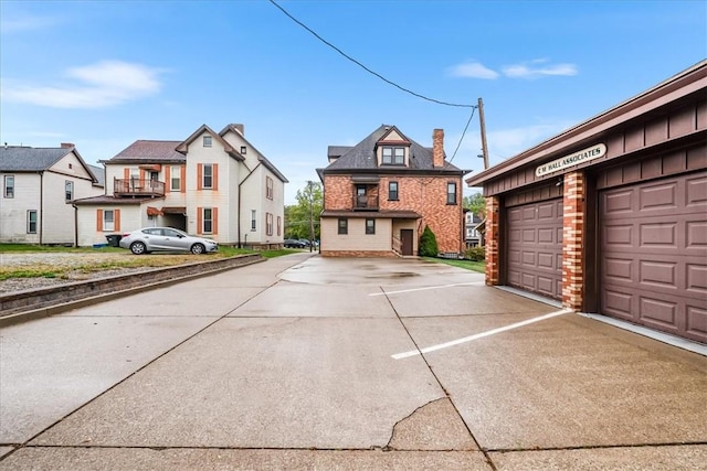 view of front of house with a garage, concrete driveway, brick siding, and a residential view