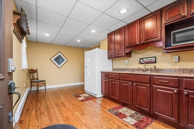 kitchen with reddish brown cabinets, white refrigerator with ice dispenser, and a sink